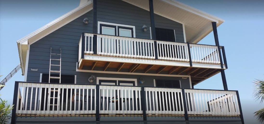 Two-story house with blue siding, white balconies, and a ladder.