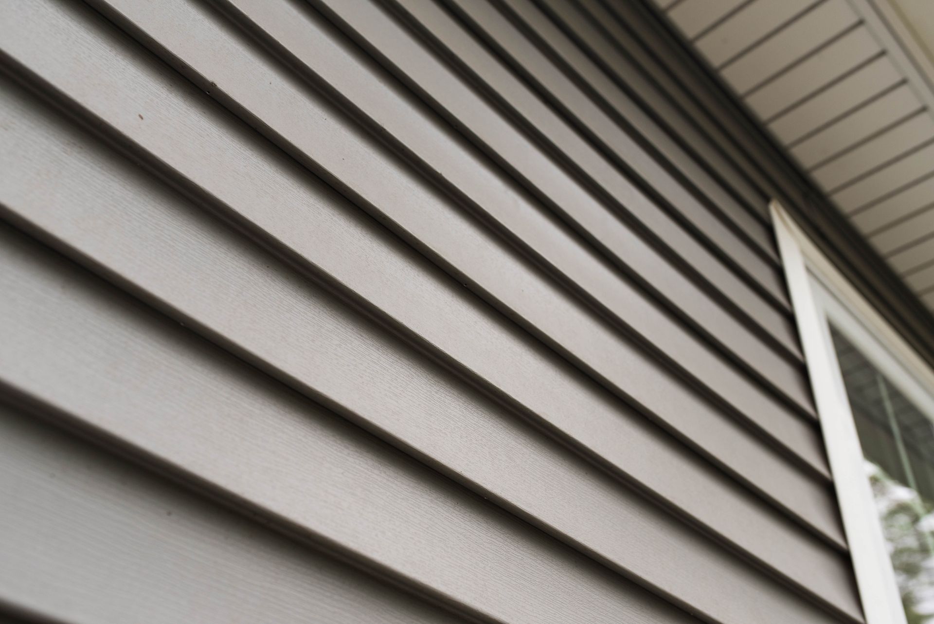 Gray horizontal siding on a house exterior, with a white trim detail on the right.