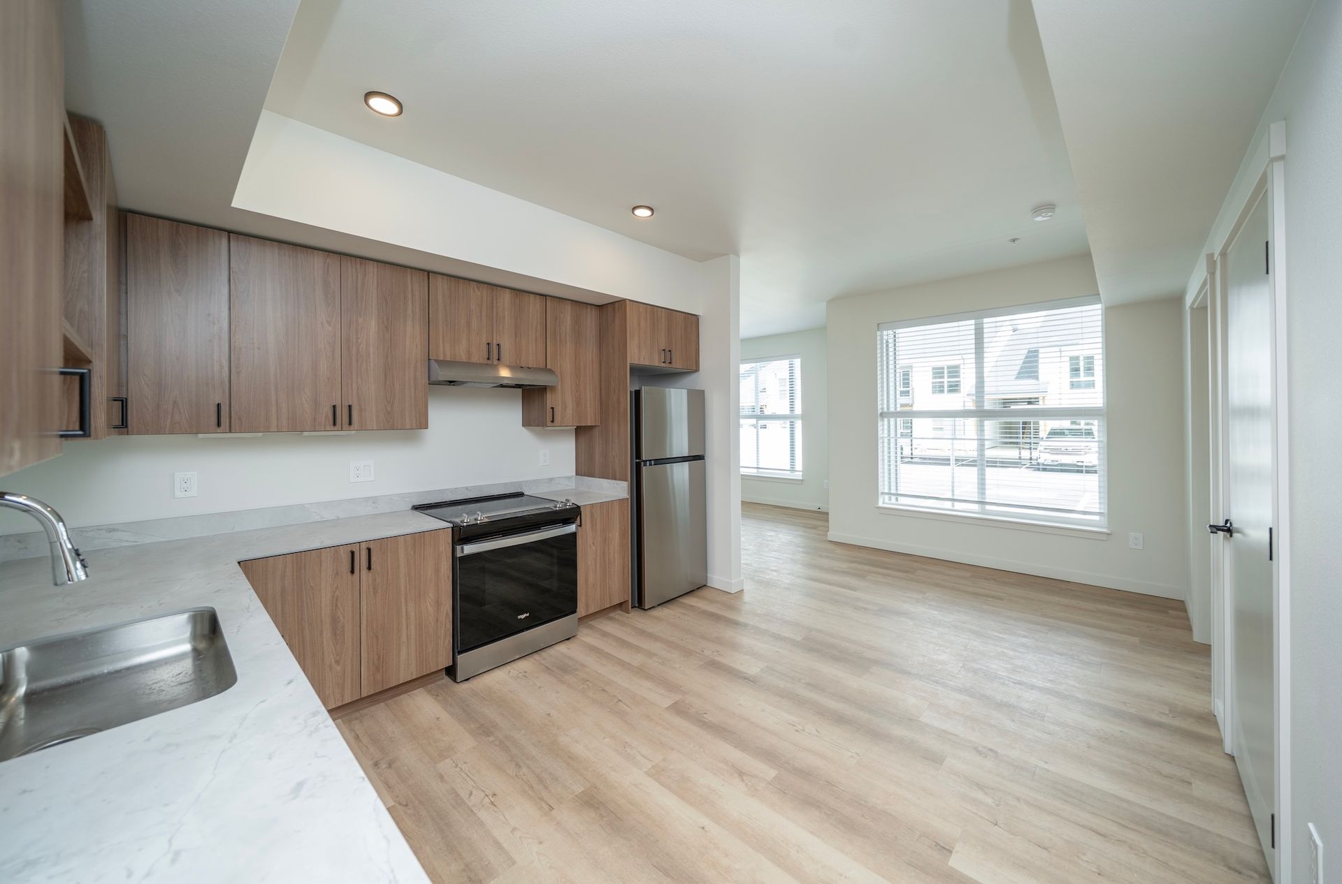 Modern kitchen with wood cabinets, stainless steel appliances, and light wood flooring.