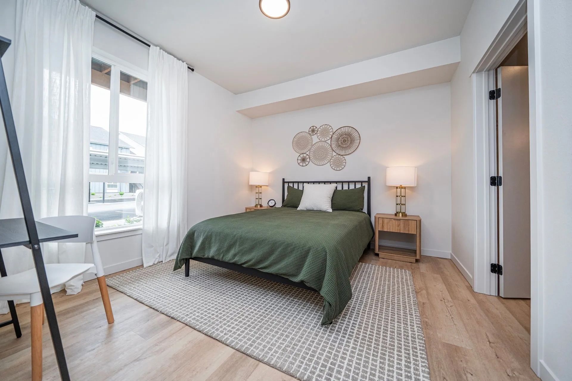 A bedroom in a Signal Point apartment in Liberty Lake, Washington, featuring a green bedspread, ligh