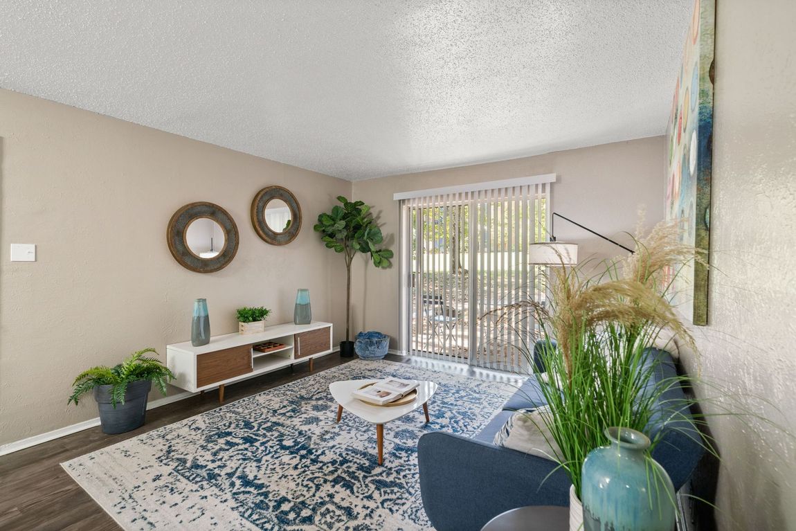 Living room with a blue couch, colorful artwork, and a patterned rug.