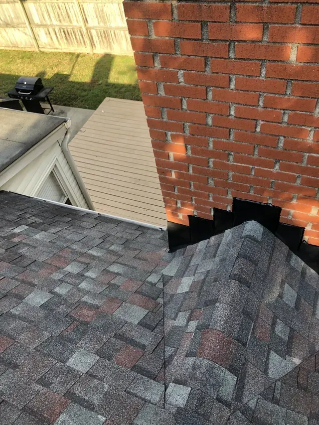Damaged chimney brickwork with a large hole where it meets the roof shingles