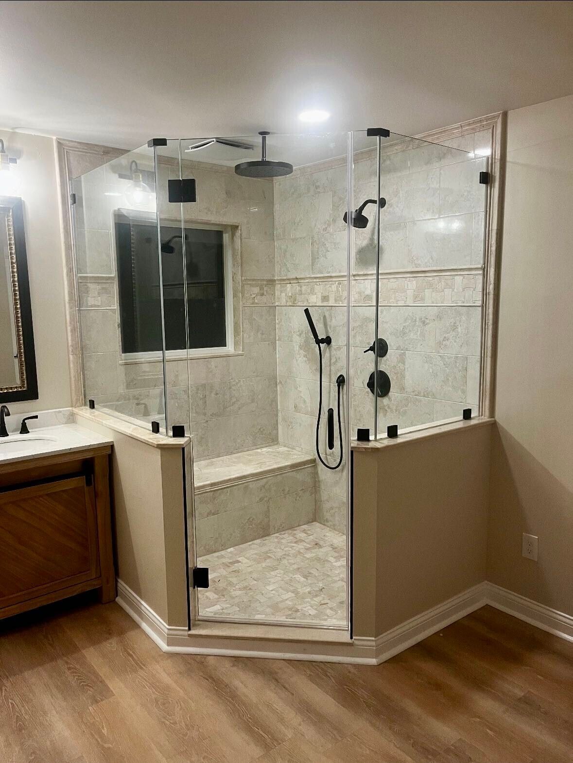 Modern bathroom with a large glass shower, bench, and multiple shower heads.
