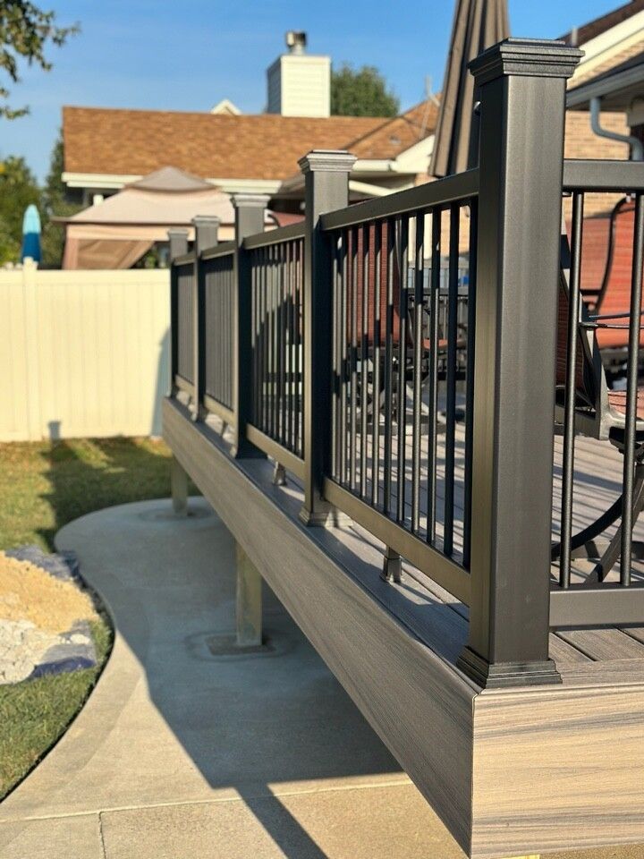 a deck with a black railing and a table and chairs on it