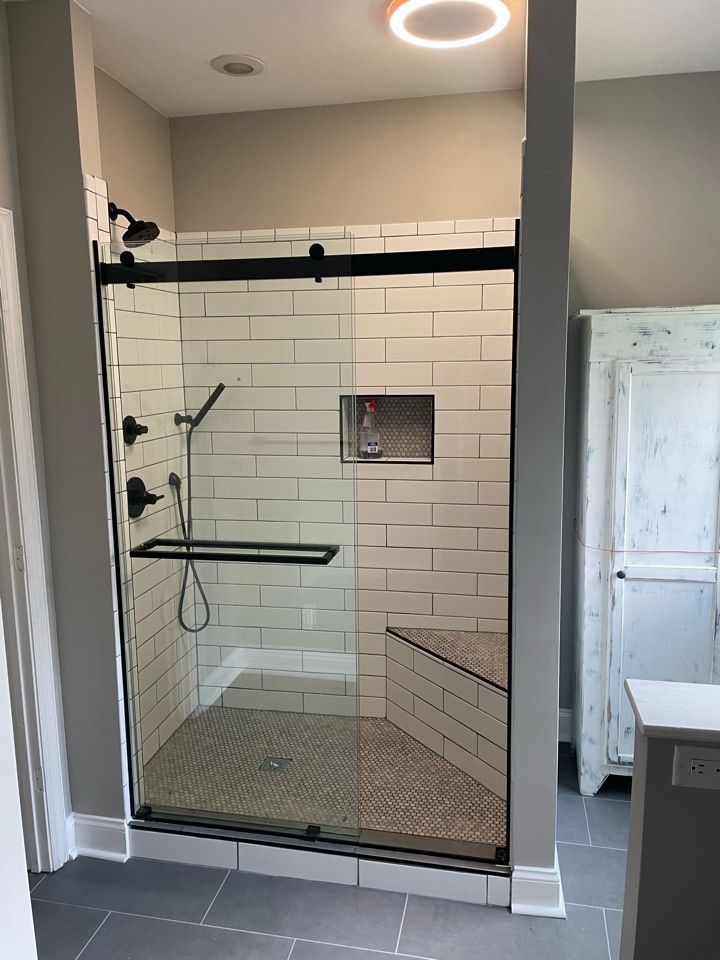 A bathroom with a walk in shower with a sliding glass door.