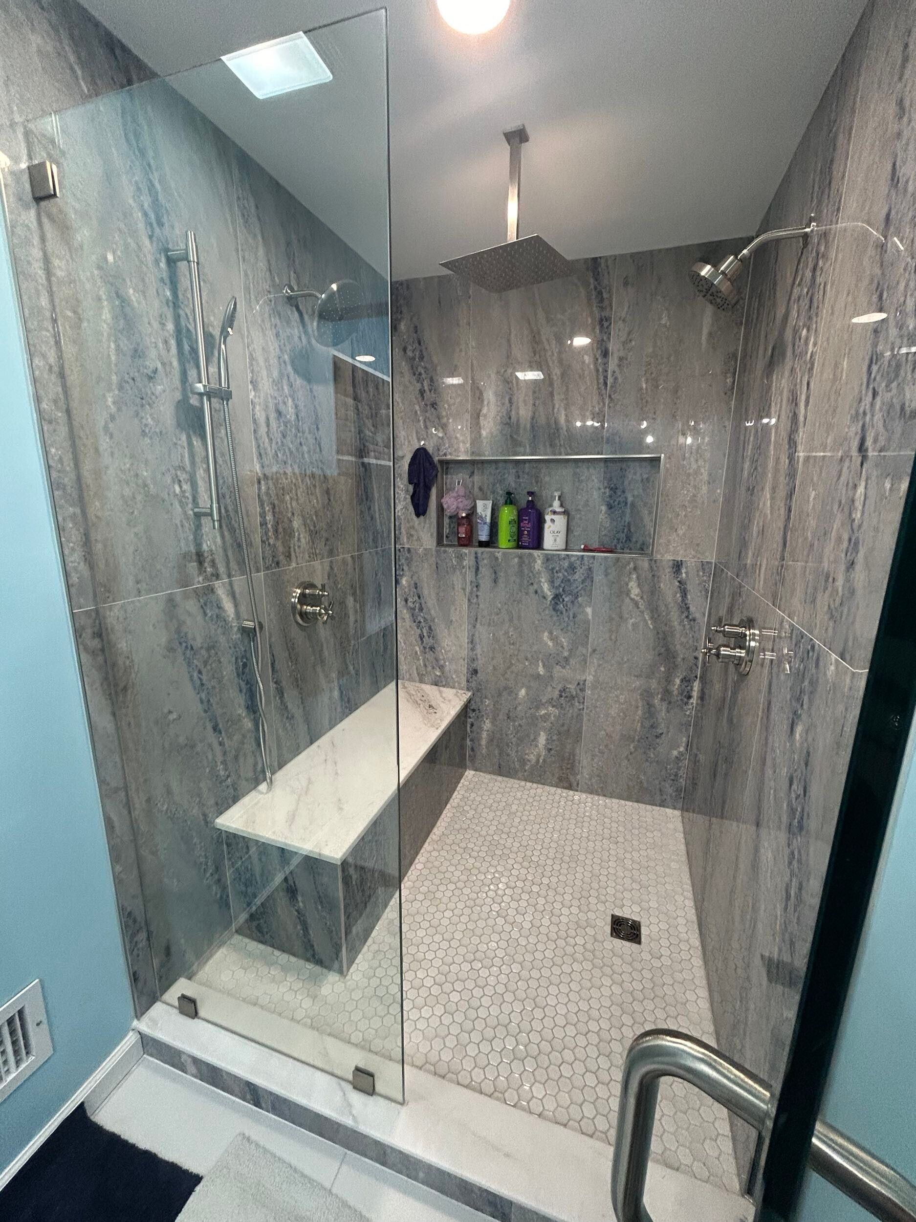 A bathroom with a walk in shower and a bench.