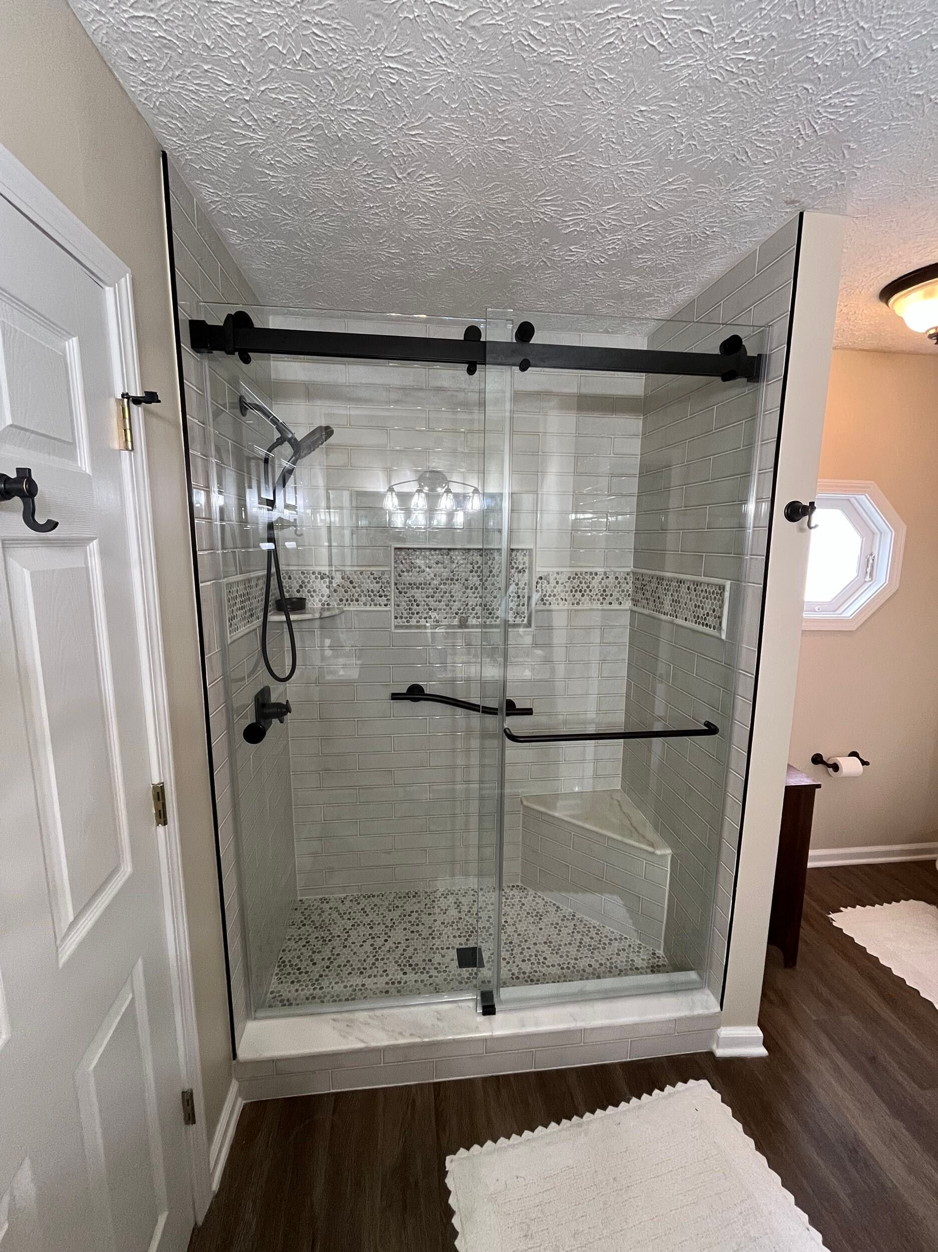 A bathroom with a walk in shower with a sliding glass door.