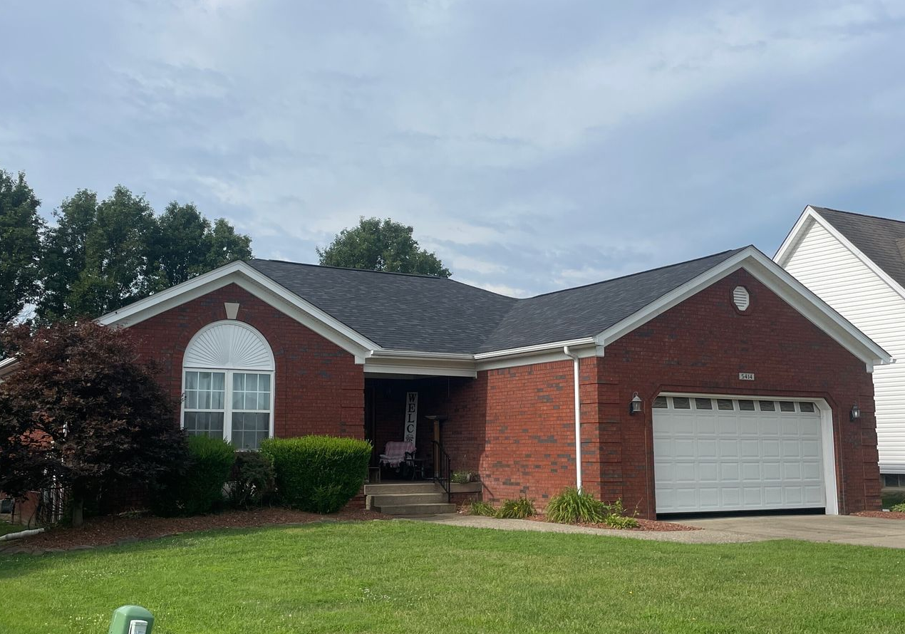 Single-story brick house with white garage and arched window under a cloudy sky