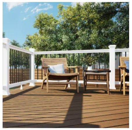 A wooden deck with a white railing and chairs