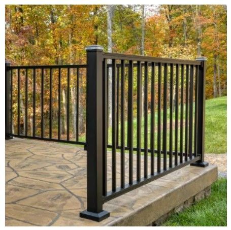 A black railing on a deck with trees in the background