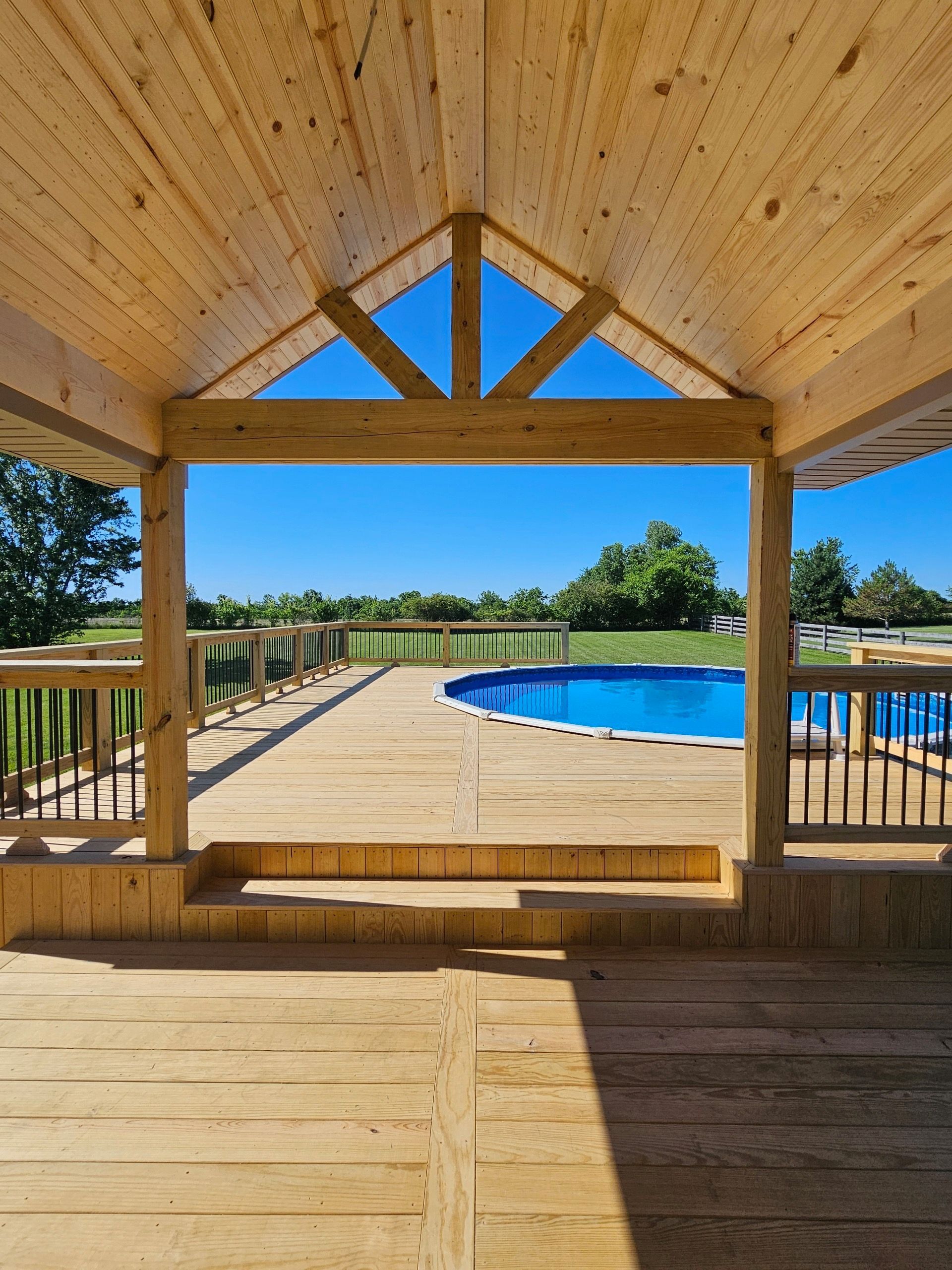 Wooden deck over a pond under a partly cloudy sky, surrounded by trees