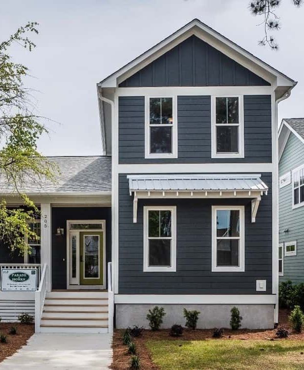 Dark gray two-story house with white trim and a front porch on a landscaped lot