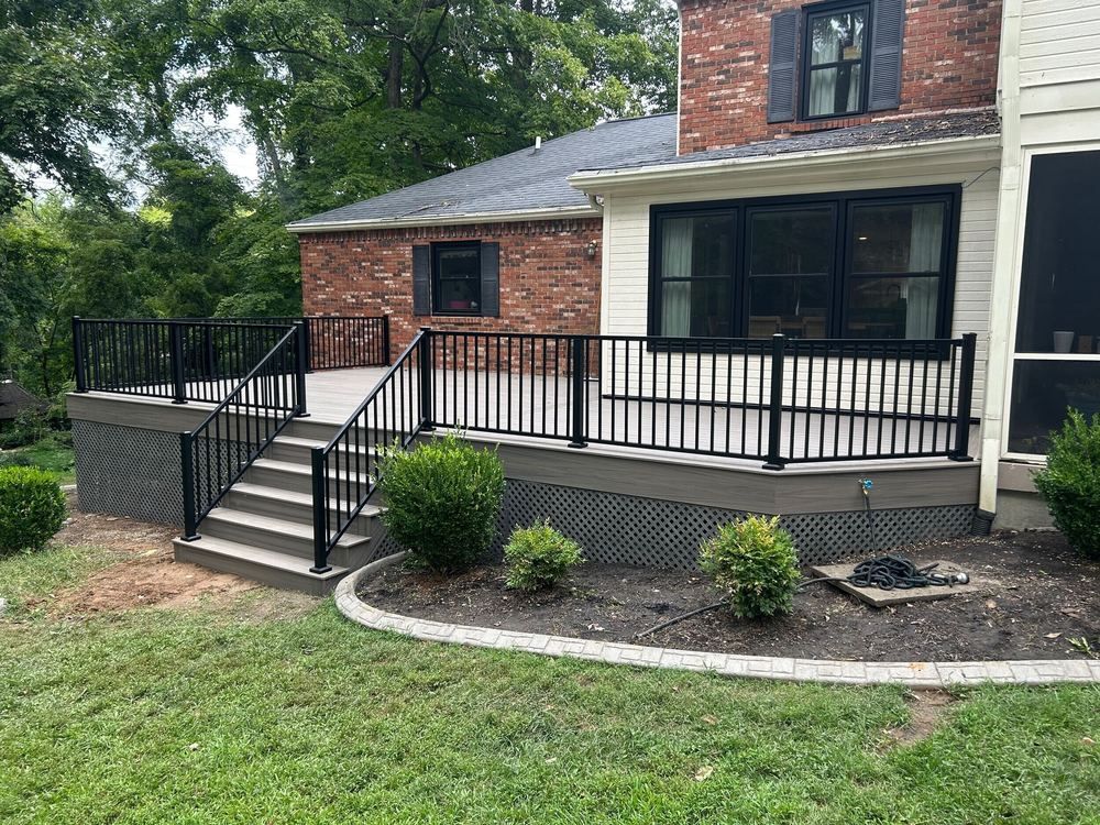 Brick house porch with black railing, front steps, and landscaped yard