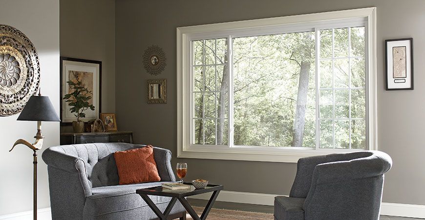 A living room with a couch and two chairs and a large window.