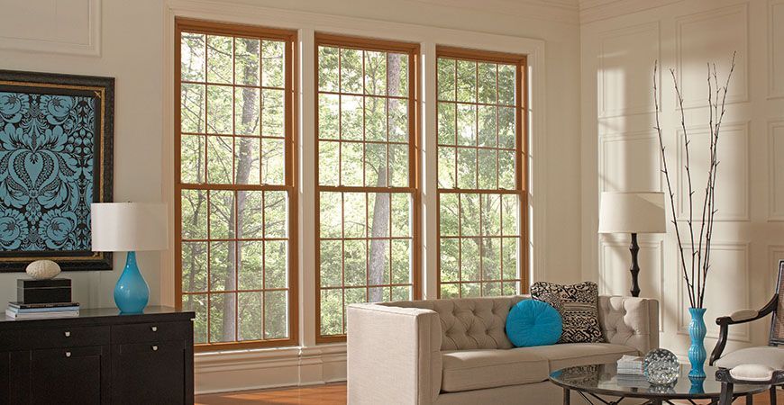 A living room with a couch , table , lamps and lots of windows.