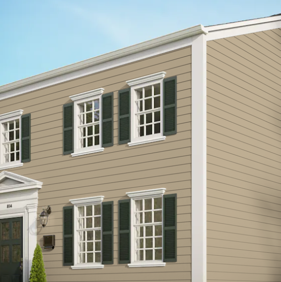 A tan house with white trim and green shutters