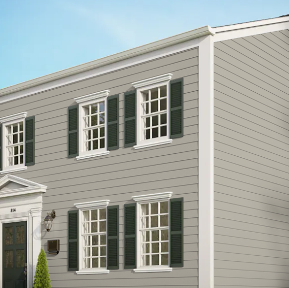 A grey house with white trim and green shutters