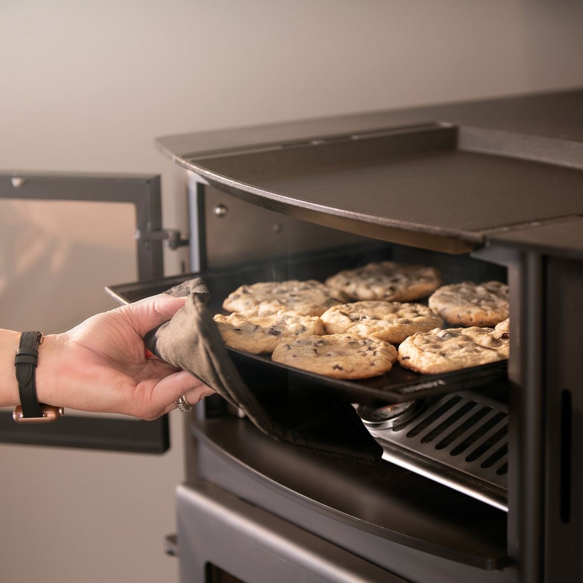 A person is taking a pan of cookies out of an oven