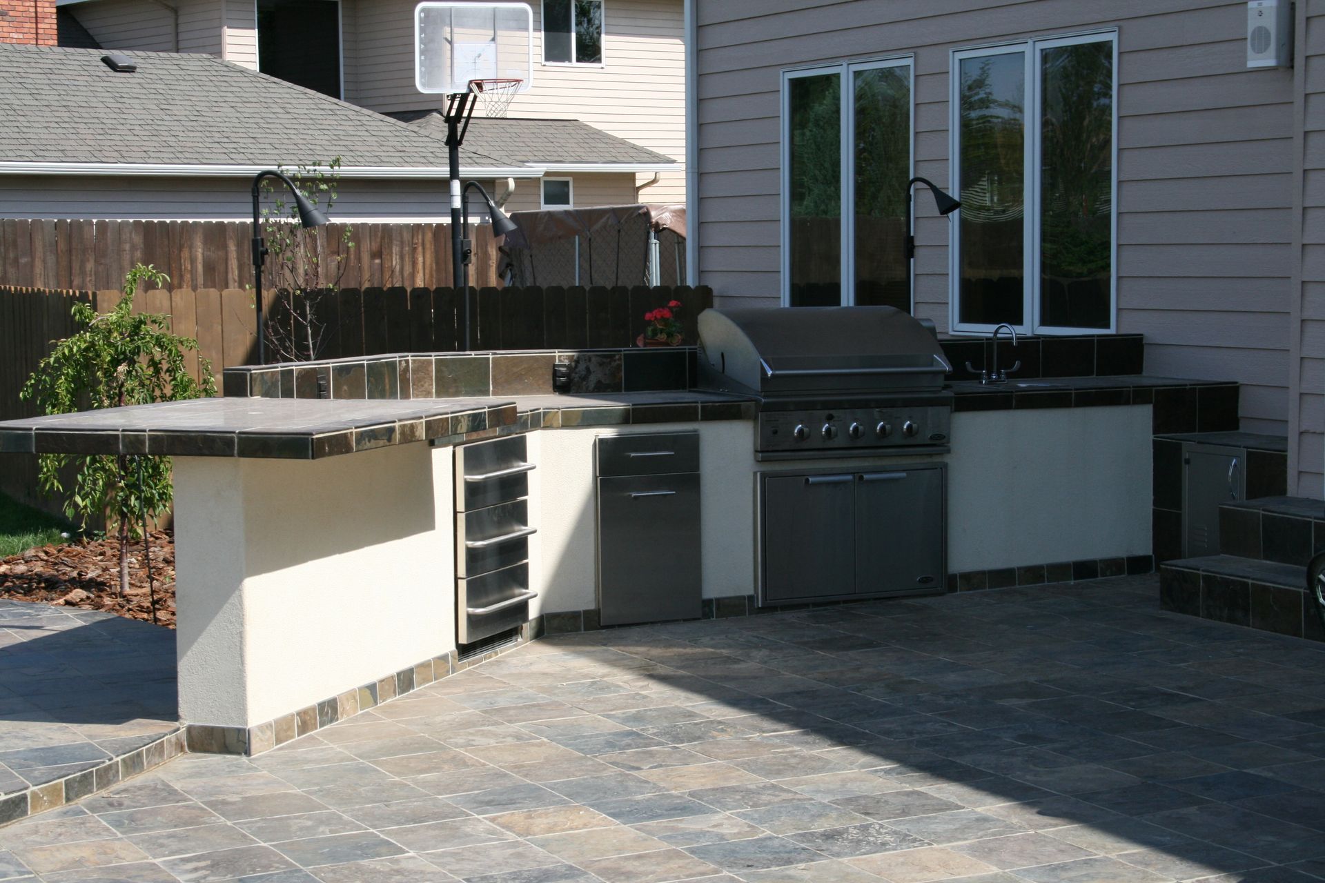 An outdoor kitchen with a grill and a basketball hoop