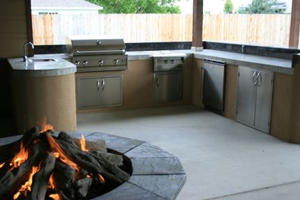 A fire pit is in the middle of an outdoor kitchen