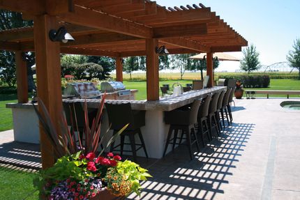 A large outdoor kitchen with a pergola over it
