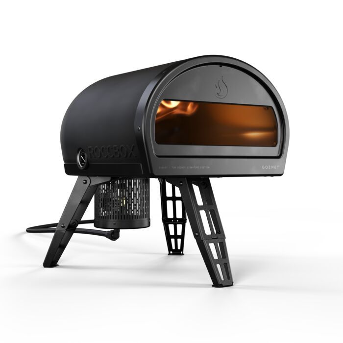 A black pizza oven is sitting on a white surface.
