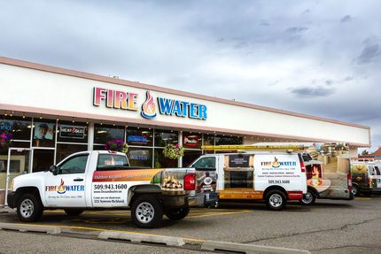 Two fire and water trucks are parked in front of a building.