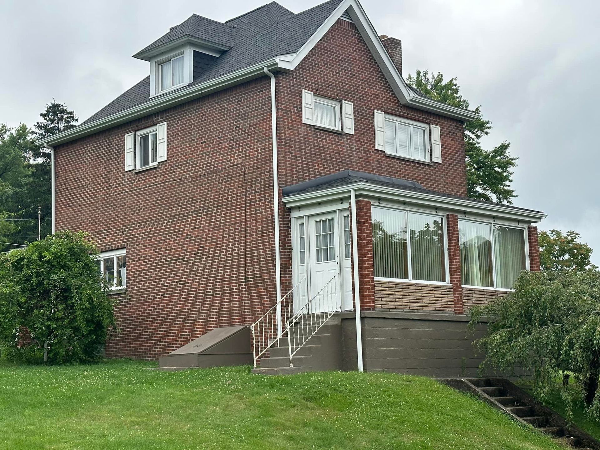 A large brick house is sitting on top of a lush green hillside.