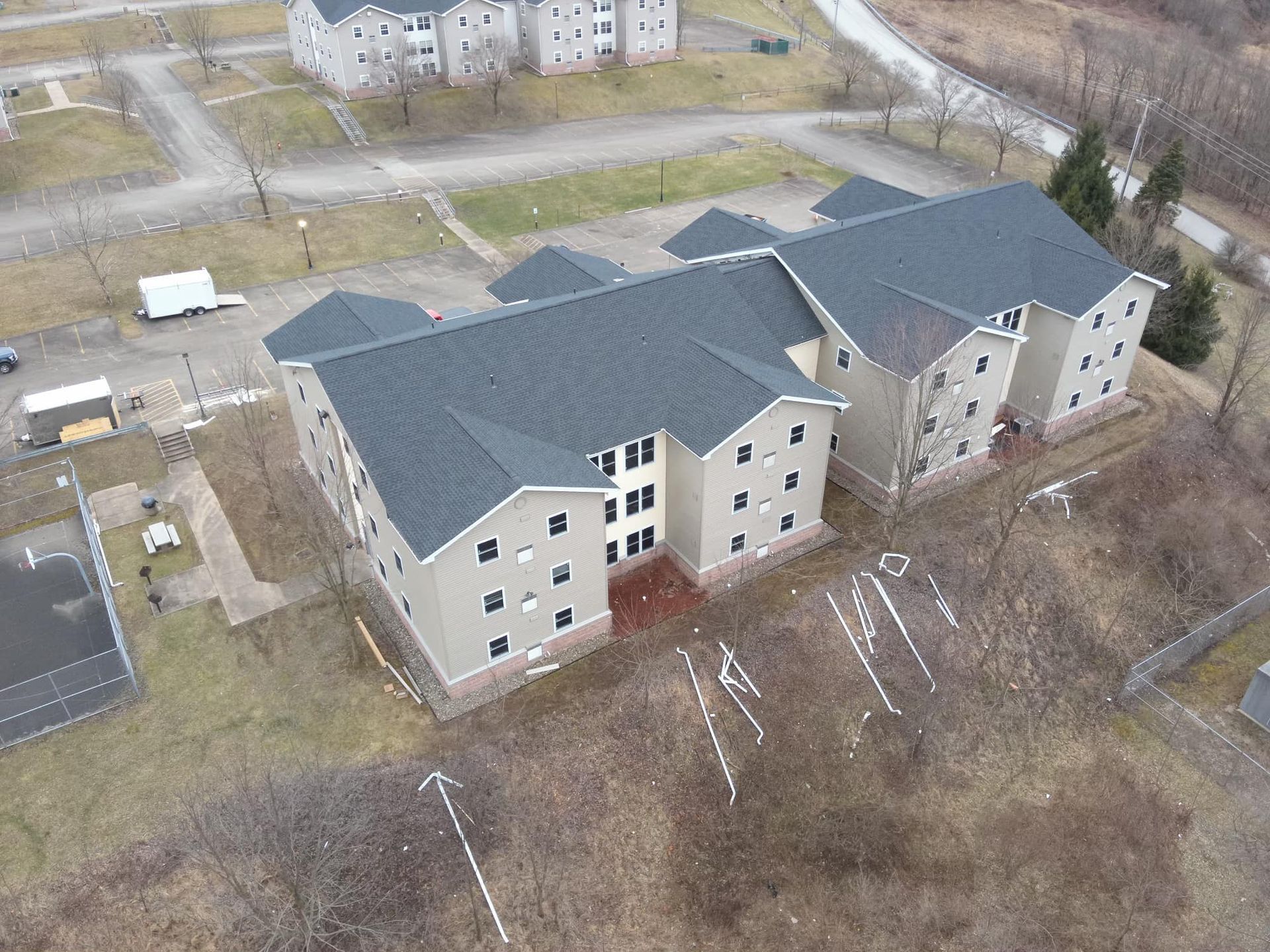 An aerial view of a large apartment building with a parking lot in front of it.