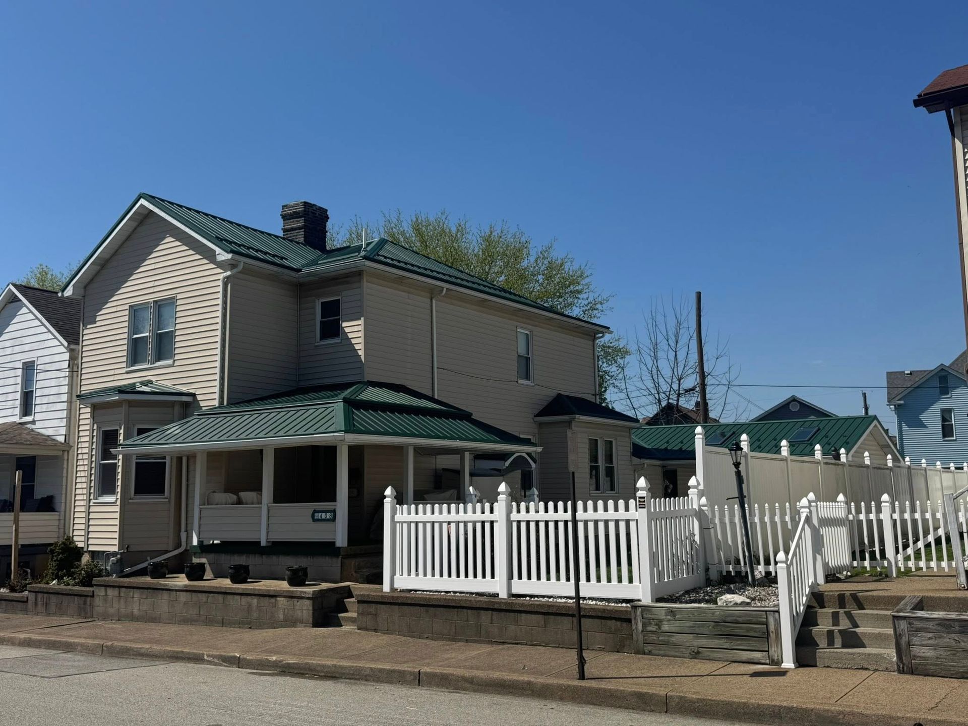 A house with a green roof and a white picket fence