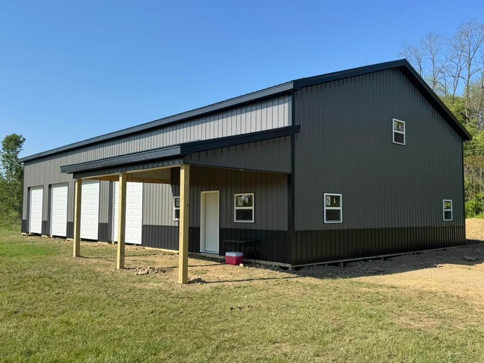 A large metal building is sitting in the middle of a grassy field.