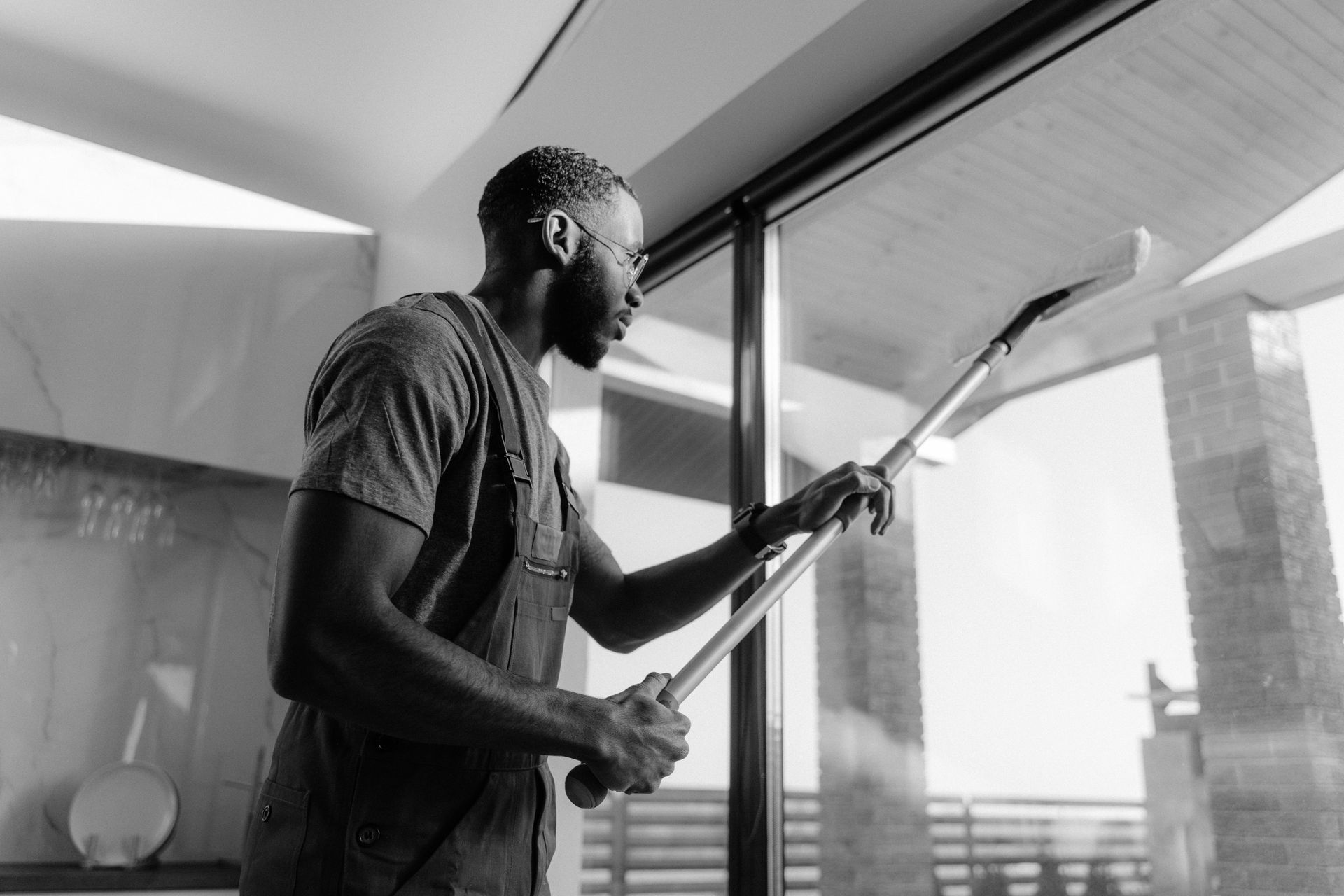Man cleaning a large window with a squeegee.