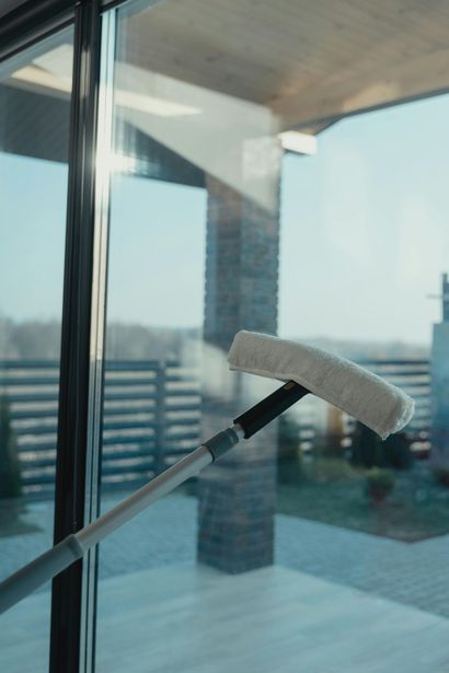Person wearing pink gloves sprays and wipes a window clean.