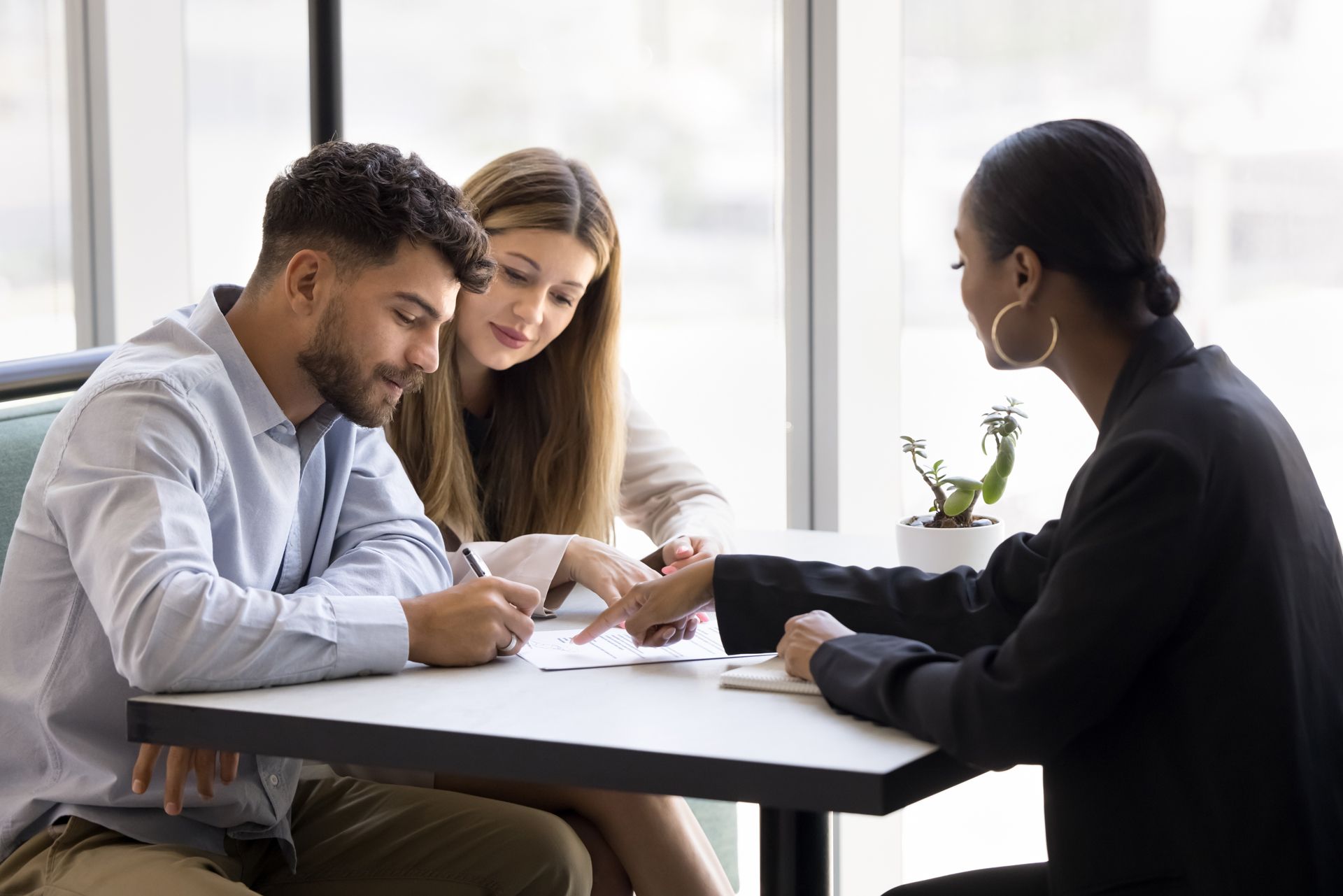 Couple signing documents at a table with a professional.