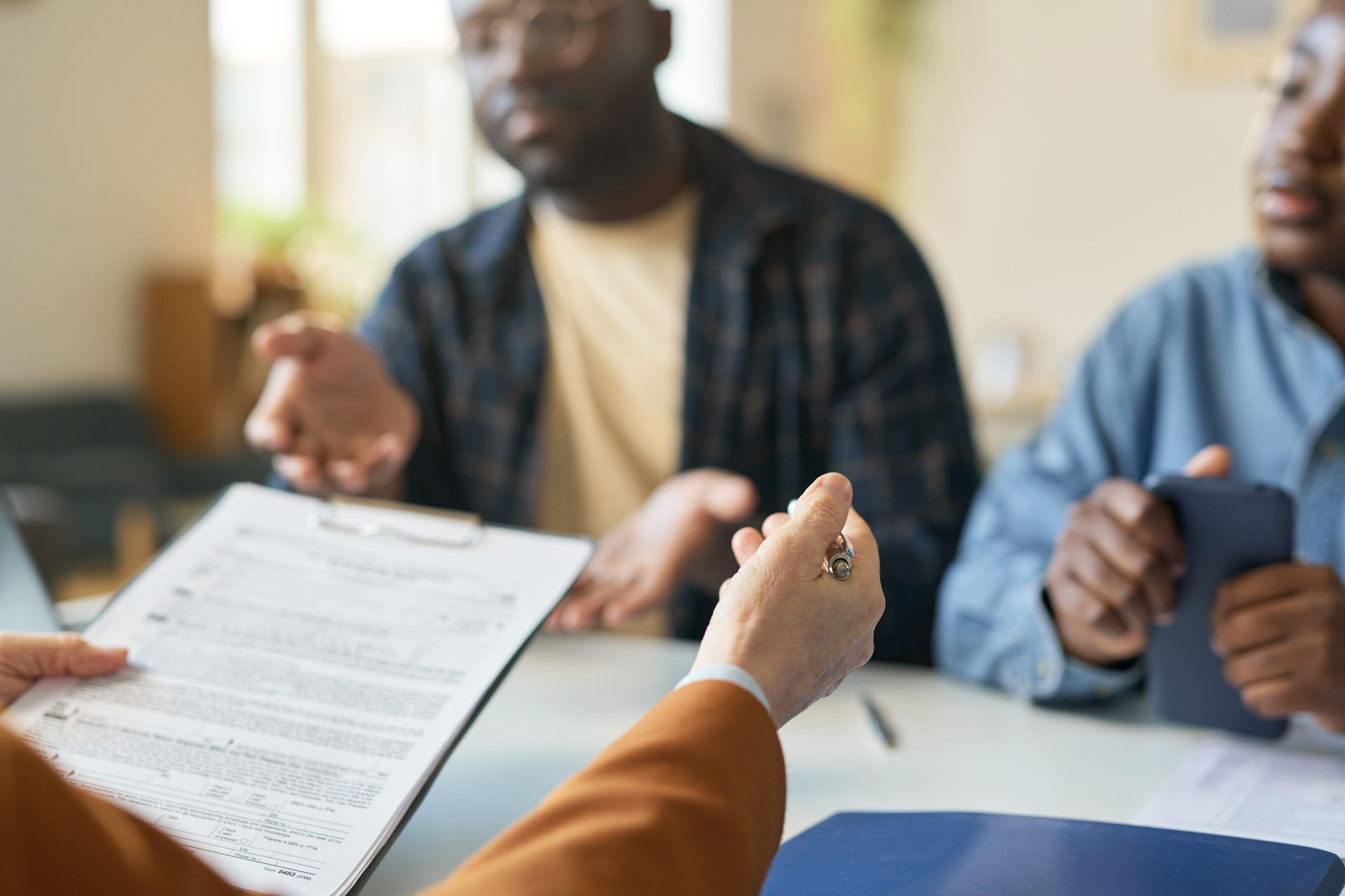 People at a table review documents, gesturing and discussing.