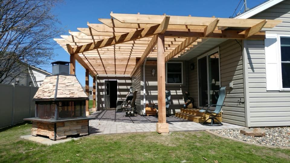 A house with a pergola and a fireplace in the backyard.