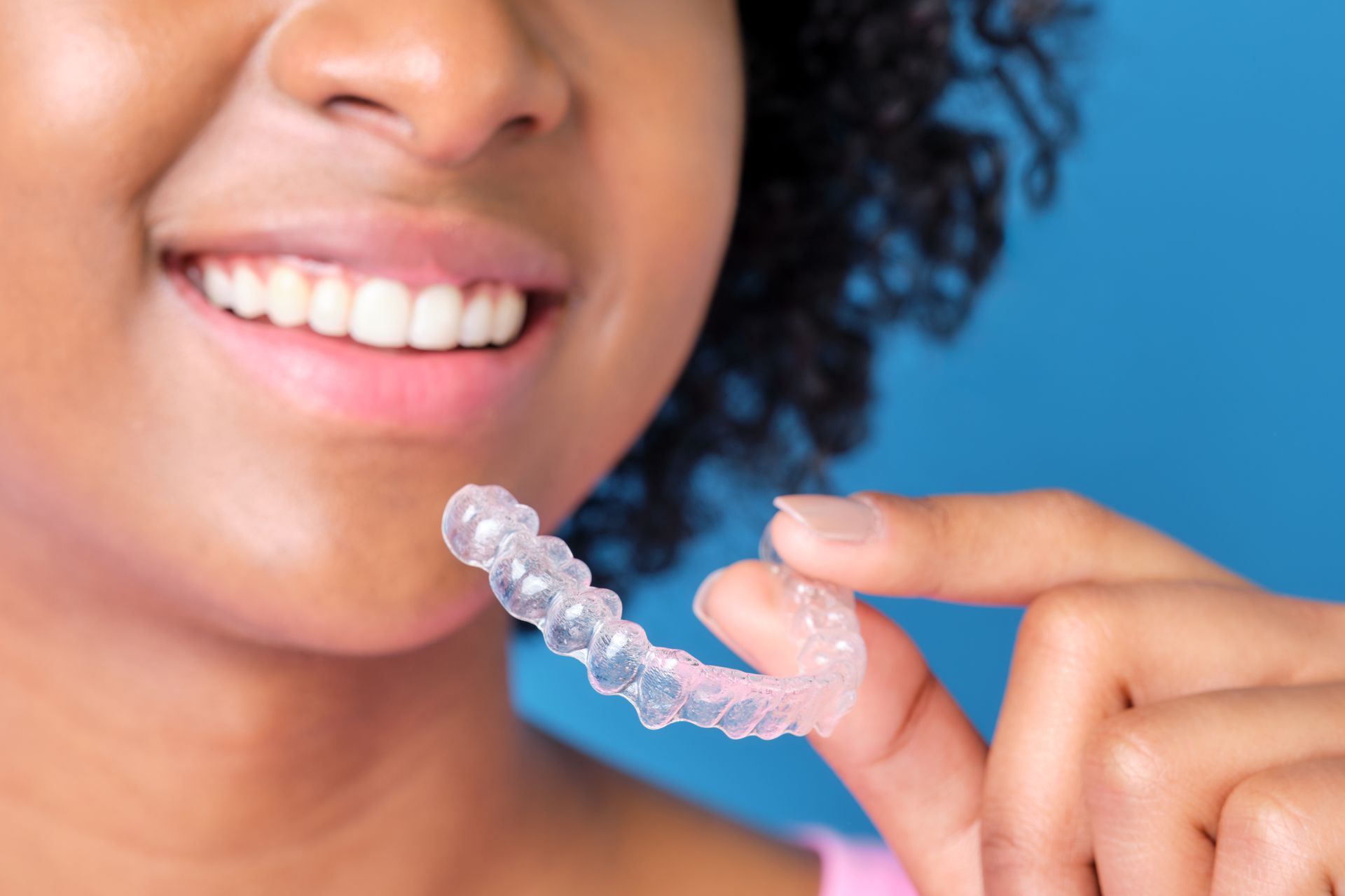 woman smiling holding invisalign clear aligners | invisible braces | Cosmetic dentist in Lynnwood WA