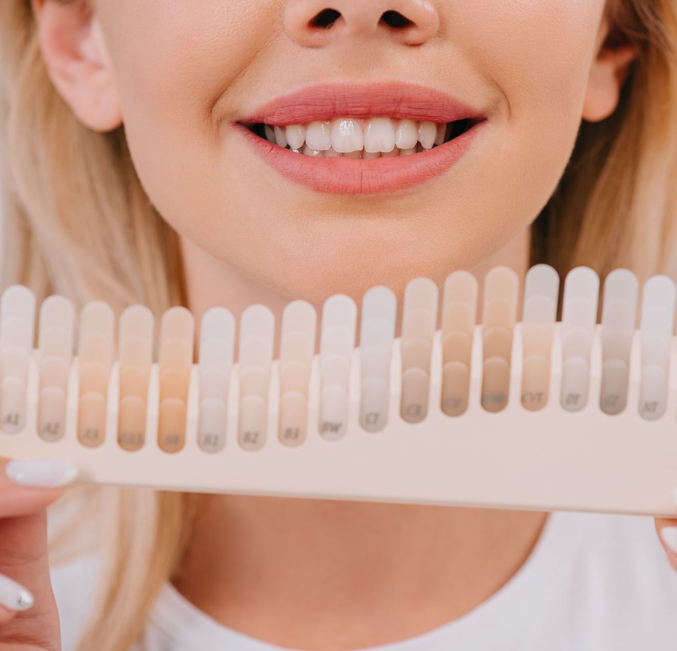 woman smiling holding up different colors of teeth whitening samples | Lynnwood WA dentist