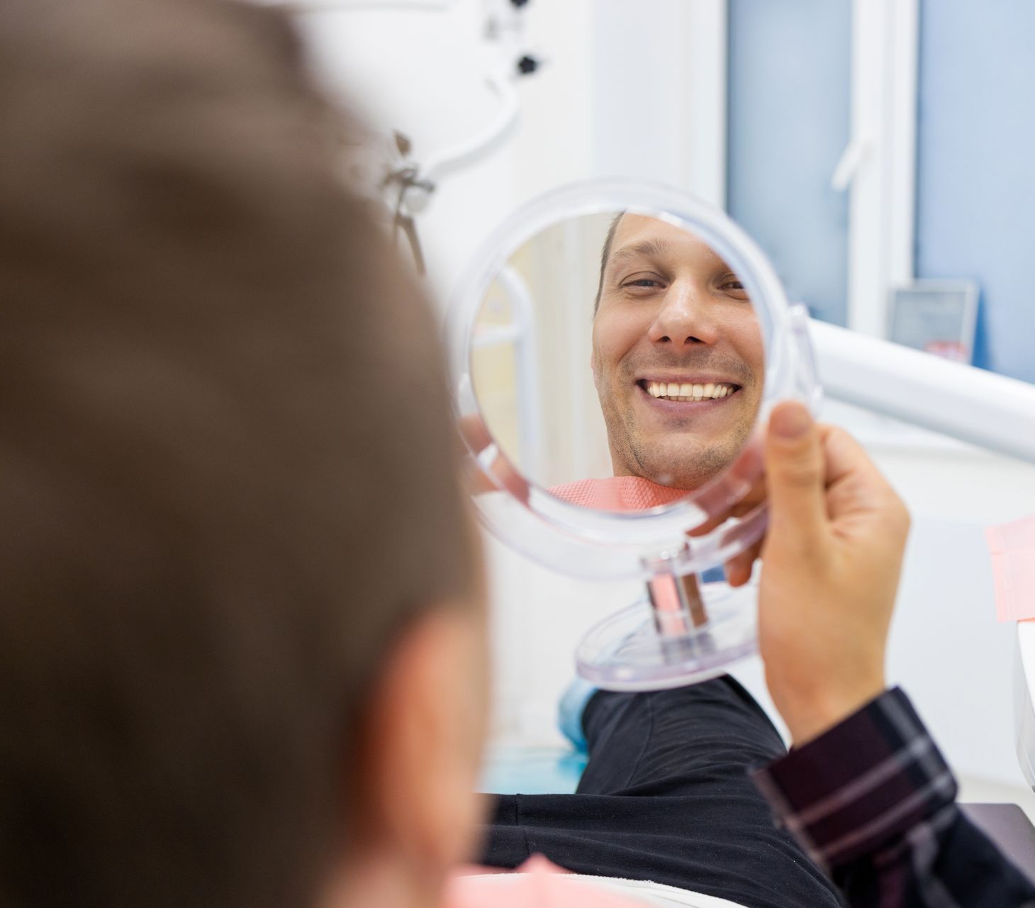 man smiling in mirror after fillings and teeth cleaning | General dentist in Lynnwood WA
