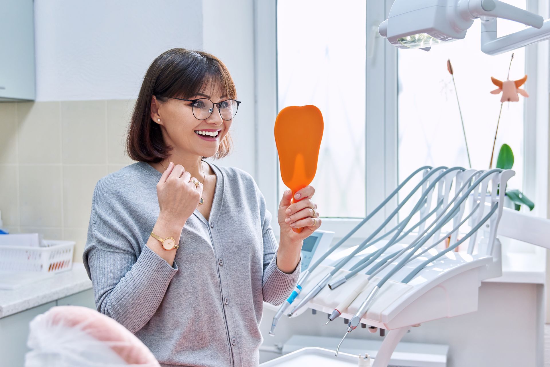woman smiling in mirror at dental office | teeth cleaning and dentures with financing | Lynnwood WA