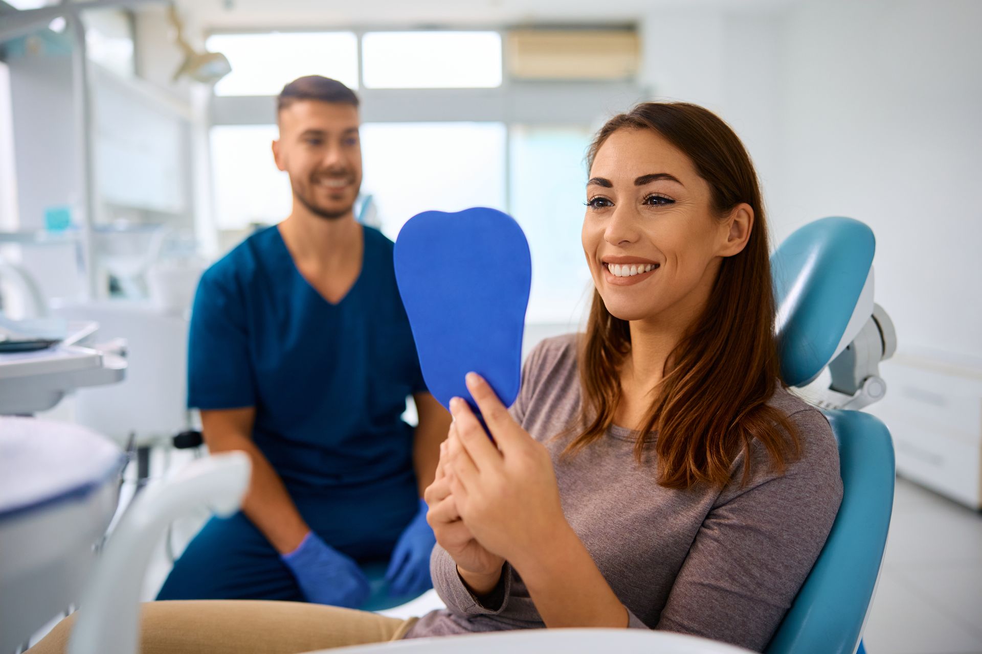 woman smiling in mirror at dental office | gum disease therapy in Lynnwood WA