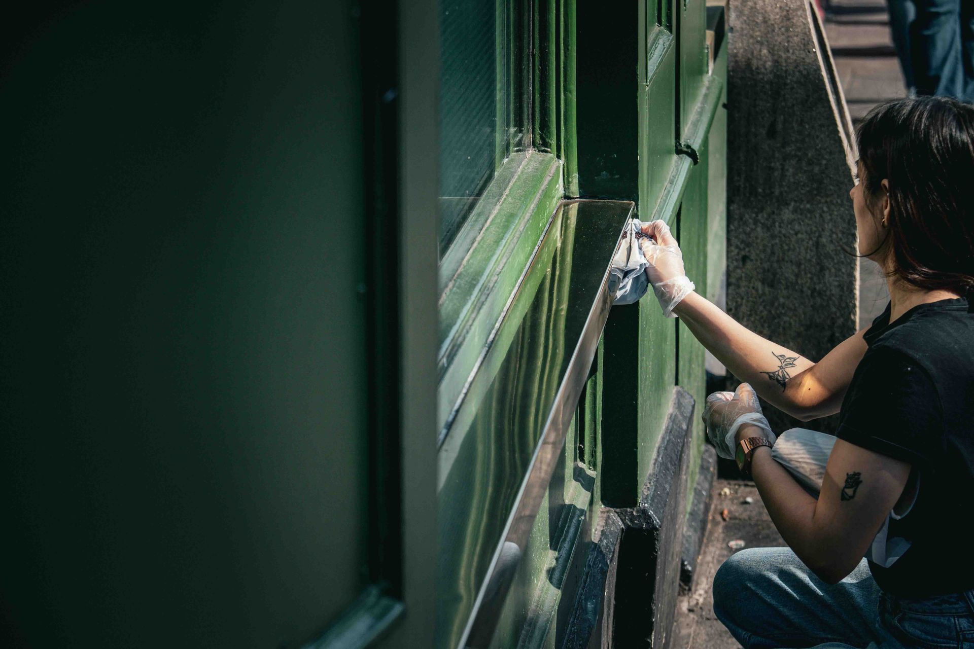 Worker crouched down cleaning a window on a commercial stree