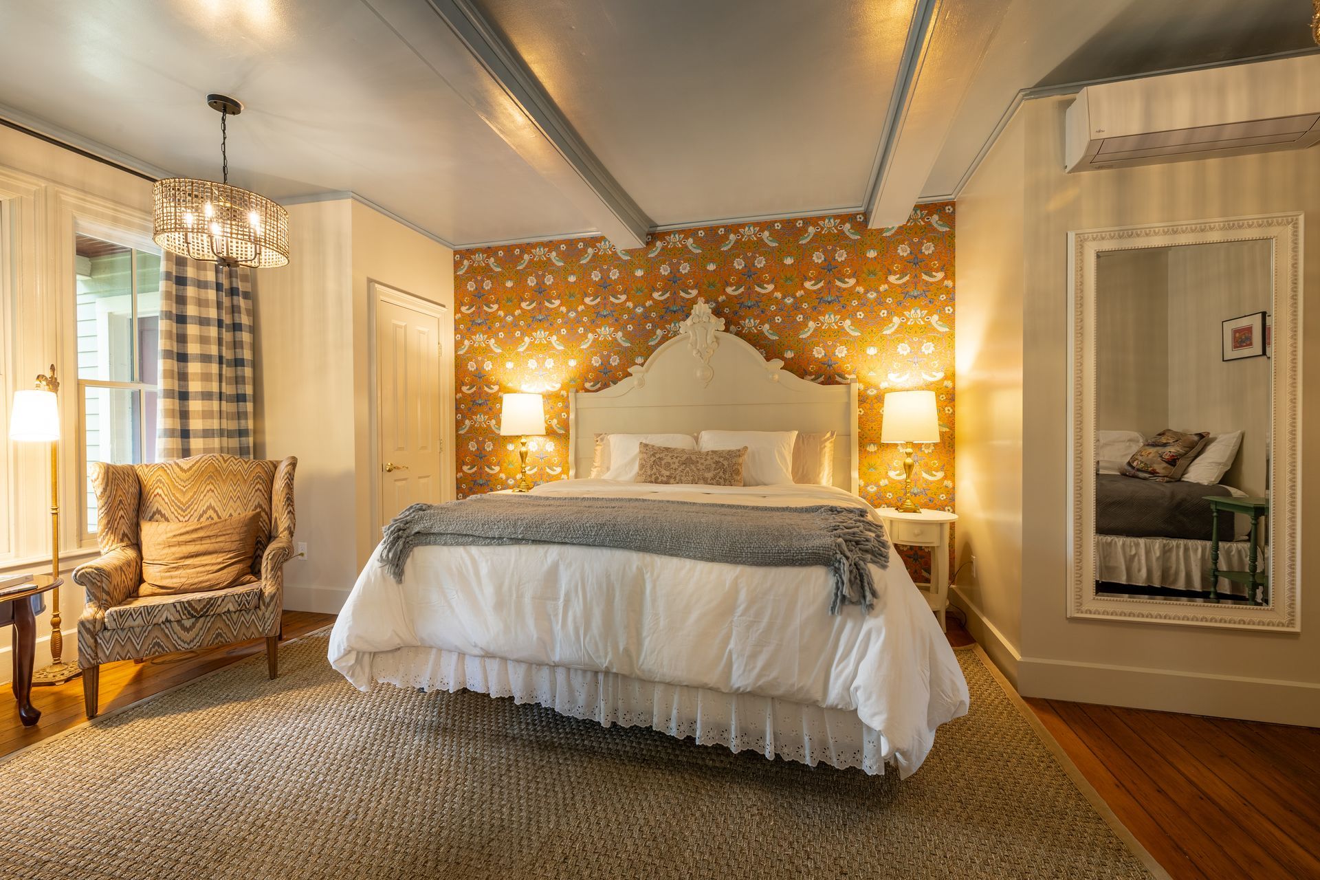 A bedroom with a king size bed , chair , and mirror.