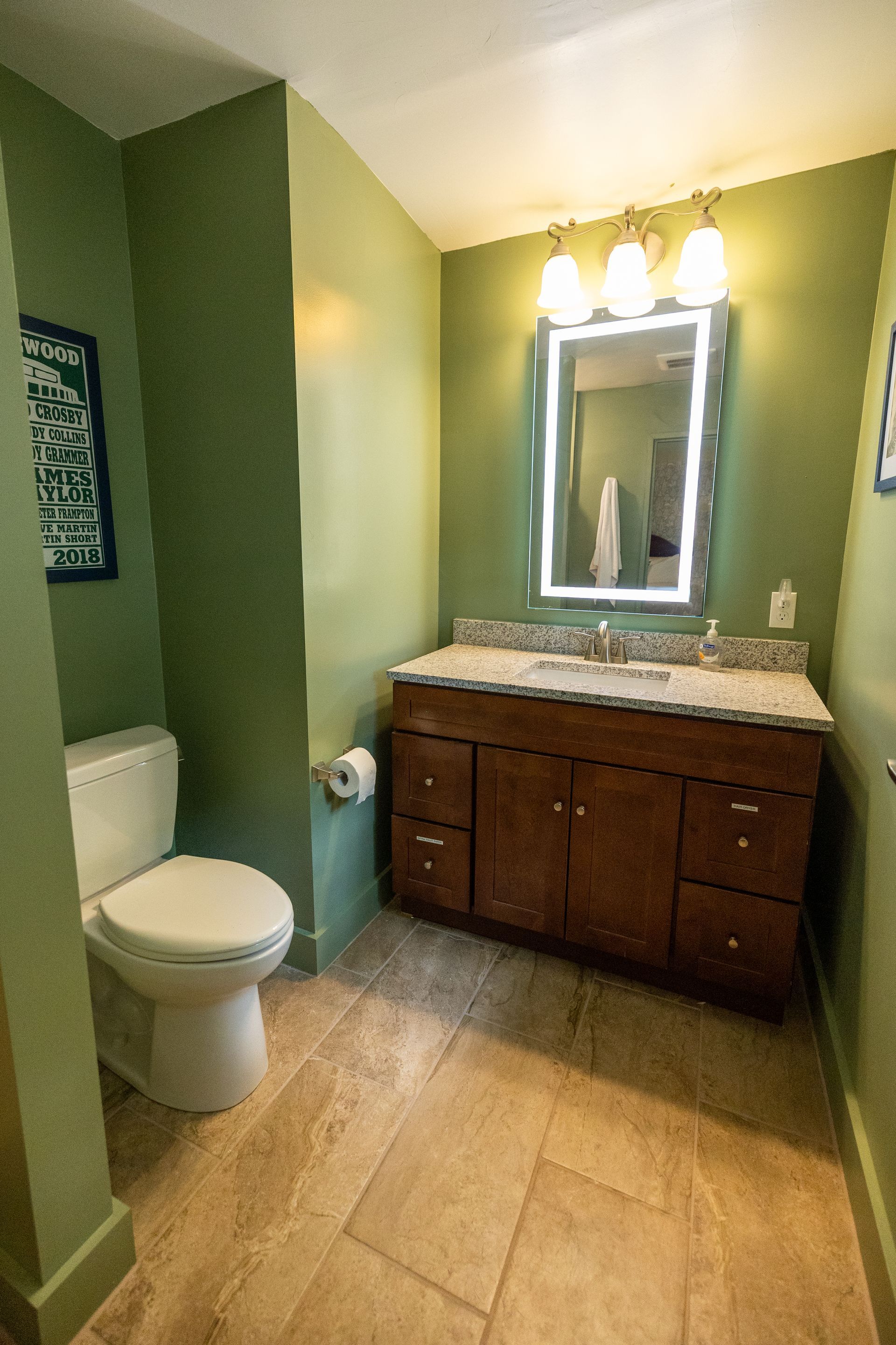 A bathroom with a toilet , sink and mirror.