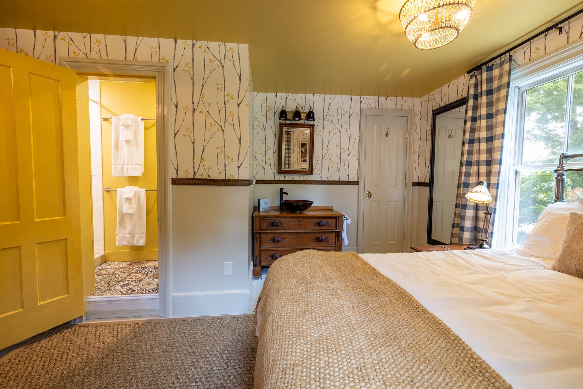 A bedroom with a bed , dresser , sink and window.