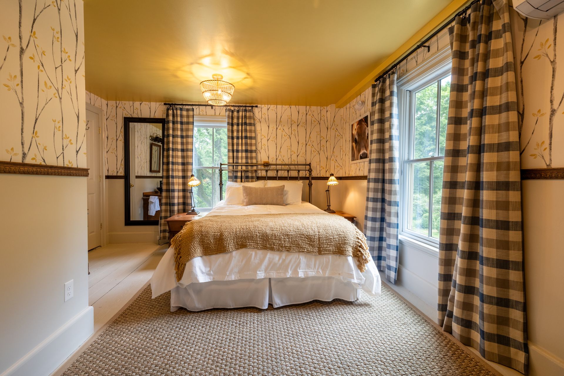 A bedroom with a king size bed , plaid curtains and a yellow ceiling.