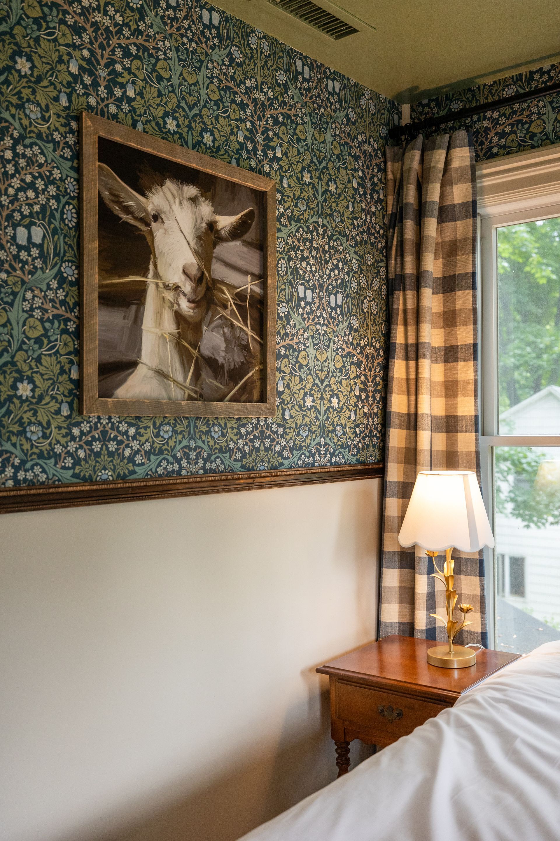 There is a picture of a goat on the wall above the bed.