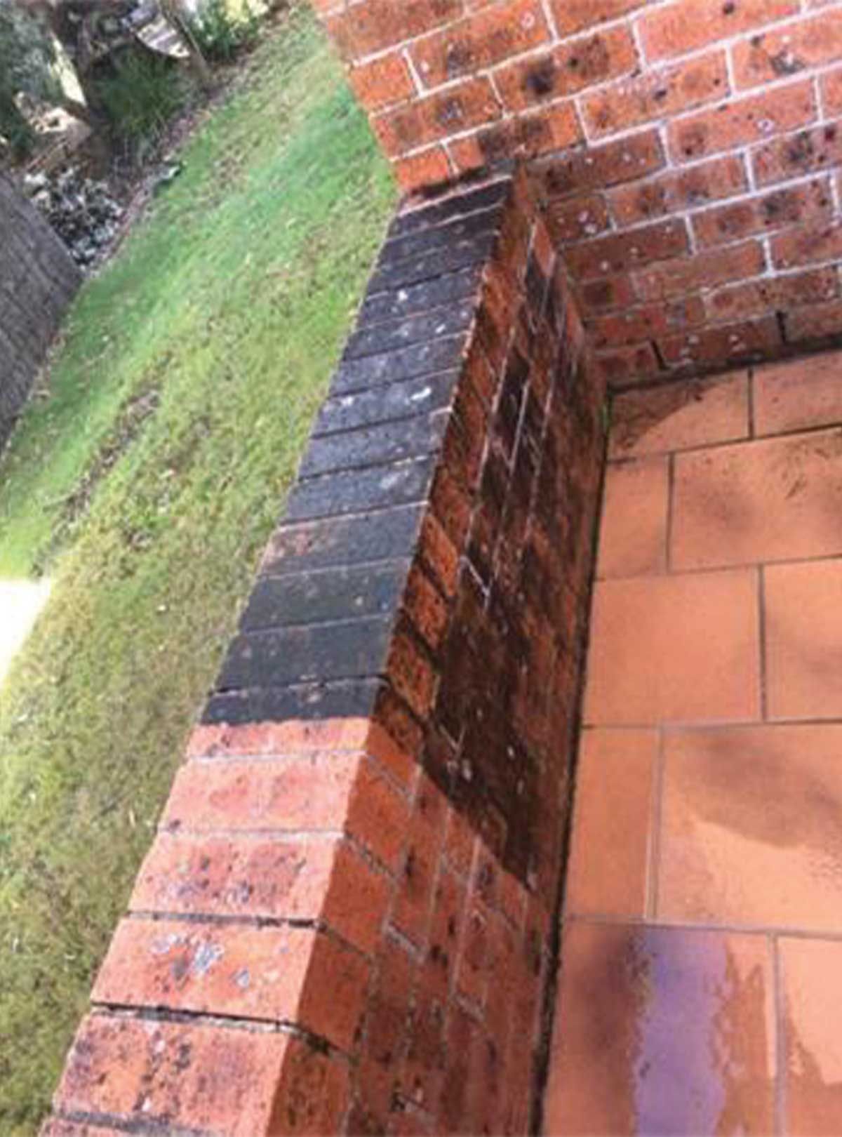 A brick wall with a tile floor next to it.