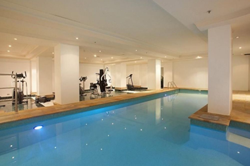 There is a large swimming pool in the middle of a gym.