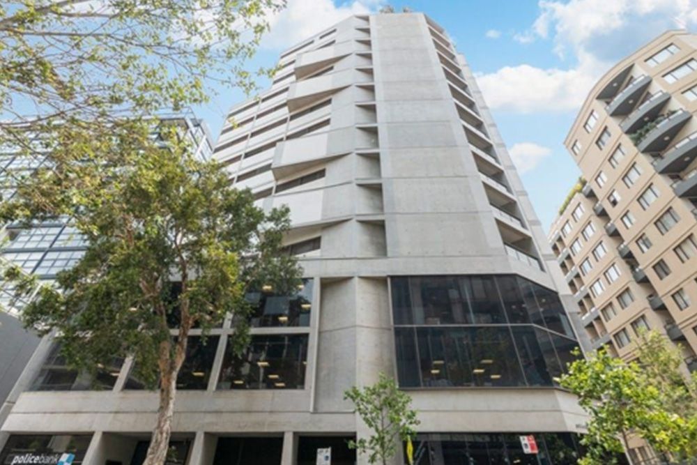A tall building with a lot of windows and trees in front of it.